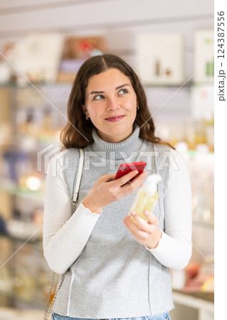 Female shopper scanning QR code on perfume in perfume shop 124387556