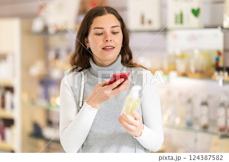 Female shopper scanning QR code on perfume in perfume shop Female shopper scanning QR code on perfume in perfume shop 124387582