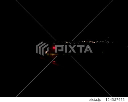 真夜中の赤信号　赤信号と遠くに光るライトの写真 124387653