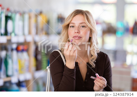 Girl housewife in cosmetic store examines goods, chooses facial powder 124387914