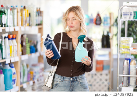 Pretty young woman customer buying spray and choosing between two bottle in store 124387922