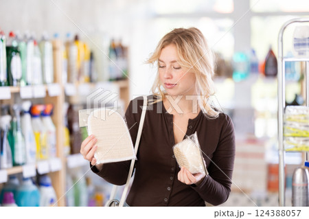 Girl housewife in household store examines goods, chooses washcloth Girl housewife in household store examines goods, chooses washcloth 124388057