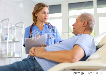 Female nurse carries out questionnaire survey of elderly male patient 124388105