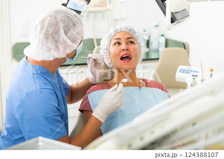 Dentist examines the oral cavity of female patient. Dental treatment in dental clinic Dentist examines the oral cavity of female patient. Dental treatment in dental clinic 124388107