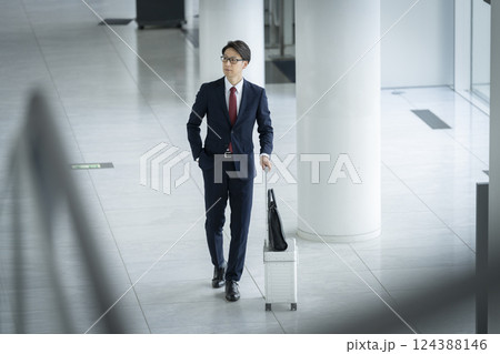 キャリーケースを持って歩く40代のビジネスマン キャリーケースを持って歩く40代のビジネスマン 124388146