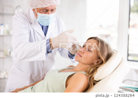 Middle-aged woman having face care by means of injection in aesthetic clinic 124388264