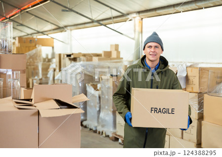 Positive warehouse worker with pasteboard box Positive warehouse worker with pasteboard box 124388295