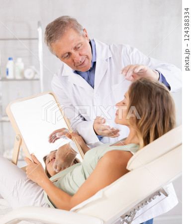 Middle-aged woman having consultation about face aesthetic while looking in the mirror Middle-aged woman having consultation about face aesthetic while looking in the mirror 124388334