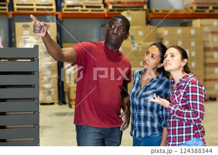 Three workers discussing working process at warehouse 124388344