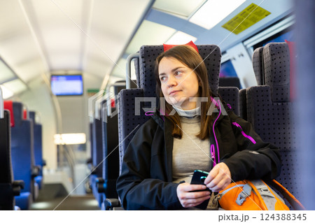 Relaxed woman with backpack and cellphone in hands traveling by train 124388345