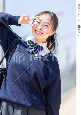 爽やかな青空の下ピースポーズで決める女子高生 124388599