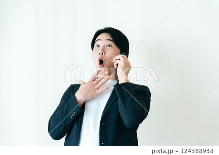 驚いた表情で電話する男性 驚いた表情で電話する男性 124388938