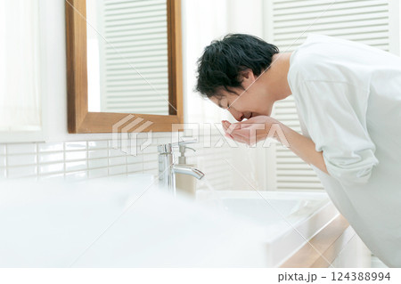洗面所で顔を洗う男性 124388994