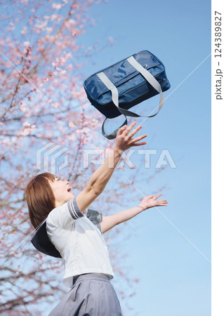 青空と桜の下で学生鞄を投げる女子高生 124389827