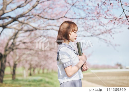 青空と桜の下の卒業少女を持つ女子高生 124389869
