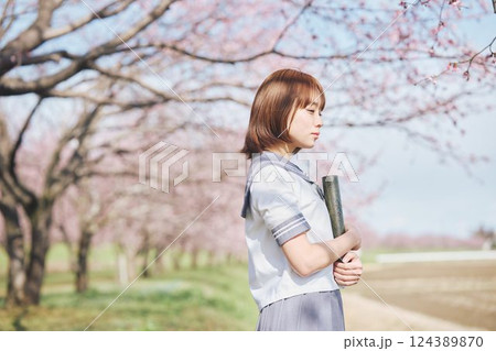 青空と桜の下の卒業少女を持つ女子高生 124389870
