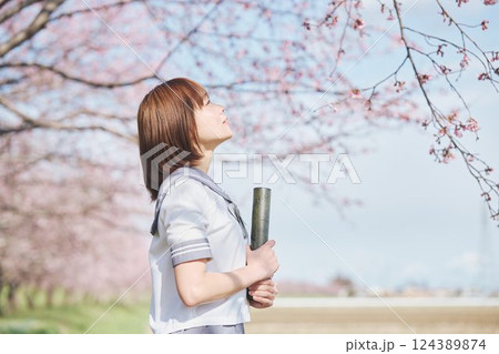 青空と桜の下の卒業少女を持つ女子高生 124389874