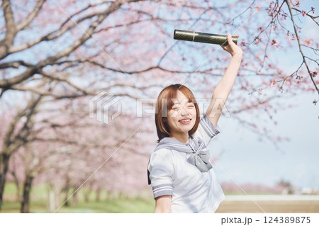 青空と桜の下の卒業少女を持つ女子高生 124389875