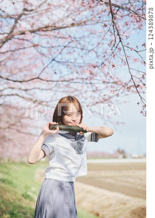 青空と桜の下の卒業少女を持つ女子高生 124389878