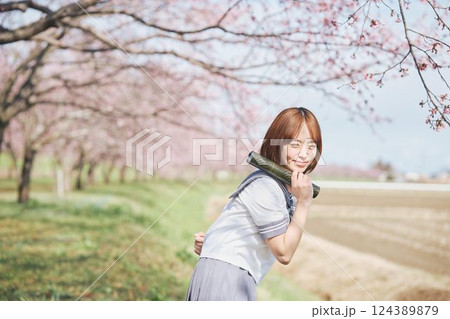 青空と桜の下の卒業少女を持つ女子高生 124389879