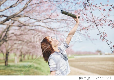 青空と桜の下の卒業少女を持つ女子高生 124389881