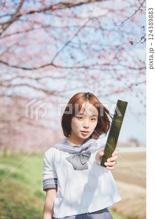 青空と桜の下の卒業少女を持つ女子高生 124389883