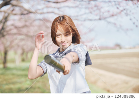 青空と桜の下の卒業少女を持つ女子高生 124389886