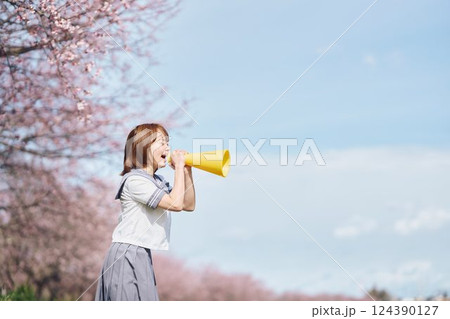 桜の下メガホンで応援する女子高生 124390127