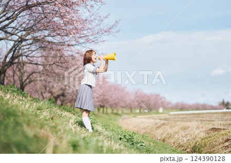 桜の下メガホンで応援する女子高生 124390128