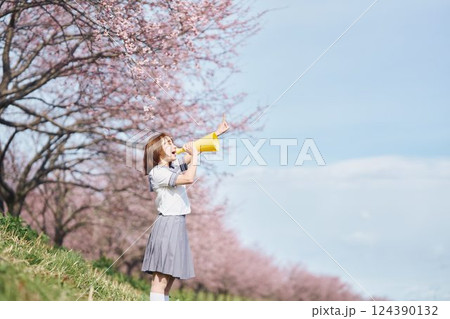 桜の下メガホンで応援する女子高生 124390132