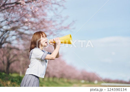 桜の下メガホンで応援する女子高生 124390134