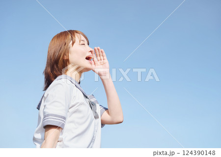 青空の下で呼びかける女子高生 124390148