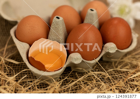 Organic brown eggs in an egg carton. Eggs in a box on straw. Broken Egg Organic brown eggs in an egg carton. Eggs in a box on straw. Broken Egg 124391877