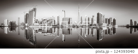 Monochrome city skyline with tall skyscrapers reflecting on calm water under a cloudy sky, Dubai Marina bay UAE Monochrome city skyline with tall skyscrapers reflecting on calm water under a cloudy sky, Dubai Marina bay UAE 124393040