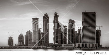 Monochrome city skyline with tall skyscrapers reflecting on calm water under a cloudy sky, Dubai Marina bay UAE Monochrome city skyline with tall skyscrapers reflecting on calm water under a cloudy sky, Dubai Marina bay UAE 124393053