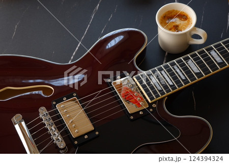 コーヒーを飲みながら、セミアコースティック（セミアコ）タイプのエレキギターを演奏しているイメージ 124394324