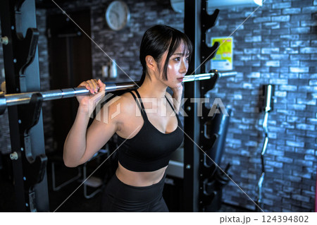 パワーラックマシンのバーベルを背負う、ジムで体を鍛えるかっこいい女性 筋トレ女子 パワーラックマシンのバーベルを背負う、ジムで体を鍛えるかっこいい女性 筋トレ女子 124394802