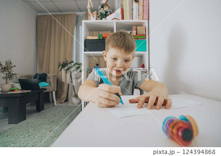 smiling boy focused on drawing at his study desk in a bright room, concept of early education, creativity in children, home schooling smiling boy focused on drawing at his study desk in a bright room, concept of early education, creativity in children, home schooling 124394868