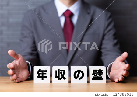 年収の壁のブロックとスーツを着たミドル男性ビジネスマン 年収の壁のブロックとスーツを着たミドル男性ビジネスマン 124395019