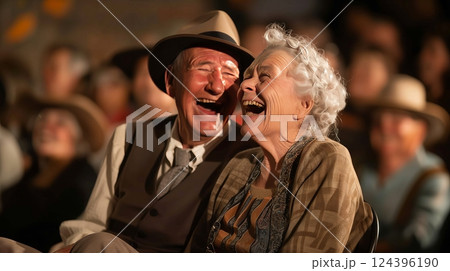 An elderly couple laughs heartily at a vintage comedy on their old TV, their bond evident in their smiles. 124396190