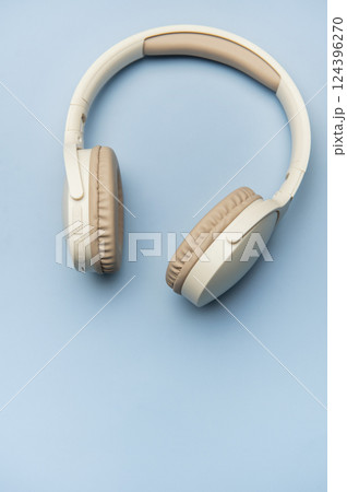 Modern wireless headphones lying on minimalist blue background Modern wireless headphones lying on minimalist blue background 124396270