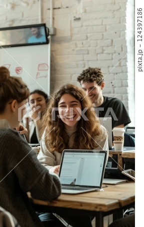 Diverse group of young professionals focused on brainstorming and collaboration in creative office space, working together on laptops, demonstrating teamwork and innovation 124397186