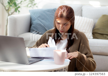 Young asian woman calculates bills finance and cost in living room at home, woman looking expense. 124397563