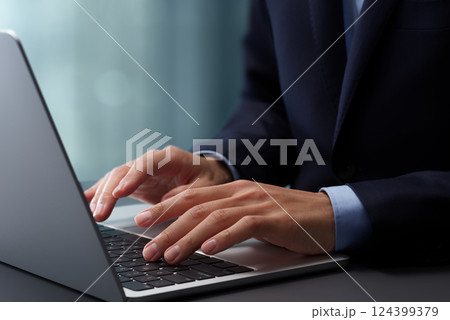 ノートパソコンのキーボードをタイピングする手のアップ。オフィスのデスクで働くスーツを着たビジネスマン 124399379