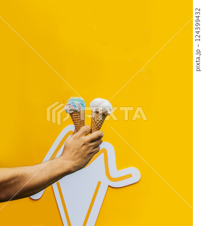 Hand holding two waffle cone ice cream isolated. Hand holding two ice cream cone on yellow background. Waffle cone ice cream concept on yellow background Hand holding two waffle cone ice cream isolated. Hand holding two ice cream cone on yellow background. Waffle cone ice cream concept on yellow background 124399432