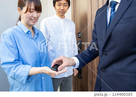 新築住宅引き渡し、鍵を渡す営業マンの手元 新築住宅引き渡し、鍵を渡す営業マンの手元 124400385
