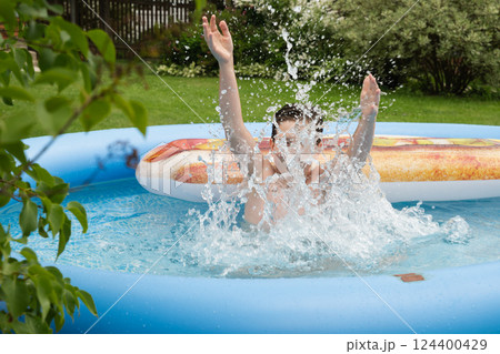 Teenager plays, swims and swimming pool in summer. Eleven years year old boy splashing in pool. Outdoors. Summer fun vacation Teenager plays, swims and swimming pool in summer. Eleven years year old boy splashing in pool. Outdoors. Summer fun vacation 124400429