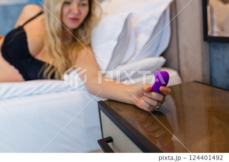 Young woman holding sex toy dildo vibrator in bed 124401492