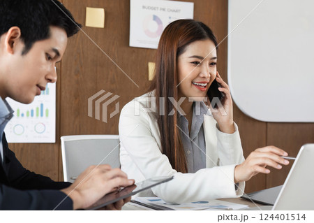 Mobile Business Communication and Productivity. A professional on the phone while working on a laptop during a meeting. 124401514