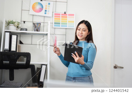 Design Process and Color Evaluation. A designer engages with her tablet and swatches to finalize design elements. 124401542
